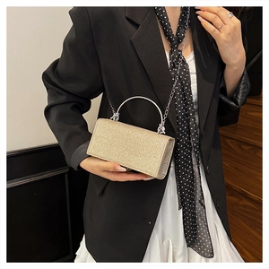 Detail of champagne gold evening clutch with glitter texture and silver metal handle