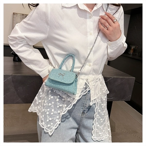 Detail of light blue sequined mini crossbody bag with silver bow and chain strap