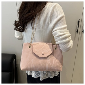 Détail du sac rose avec texture marbrée et chaîne dorée sur l'épaule d'un mannequin
