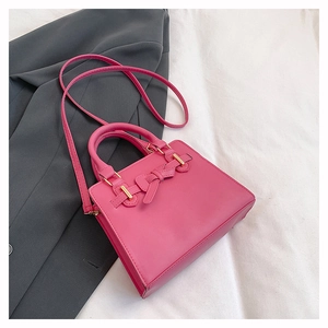 Vue détaillée de dessus d'un sac à main rose fuchsia avec nœud en cuir sur blazer et lit