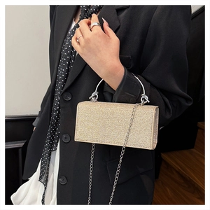 Chic gold sequin evening clutch bag with round metal handle and chain strap on model