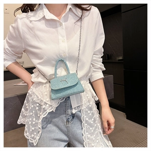 Detail of a mini sky blue sequin crossbody bag with a delicate silver bow and metal chain