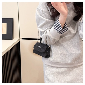 Detail of black glitter crossbody bag with silver metal bow and elegant chain strap