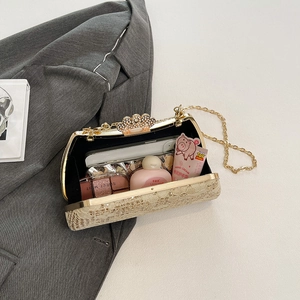 Detailed view of golden evening clutch with crown pearl clasp and chain on gray fabric