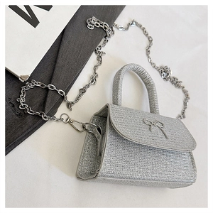 Detail of silver glitter handbag featuring a metal bow buckle and elegant chain strap
