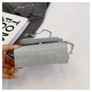Macro detail of silver glitter handbag showing the wide base and metallic chain strap