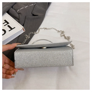 Close-up of silver sequin evening bag with round metal handle and chain strap