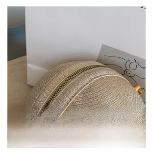 Detail of a gold spherical evening bag featuring a smooth metal zipper and chain hook