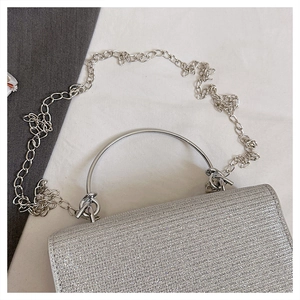 Close-up of sparkling silver sequin fabric texture and metallic ring handle on the evening bag