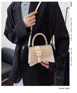 Gros plan détaillé du sac boîte beige avec rabat pailleté doré et fermoir floral en métal
