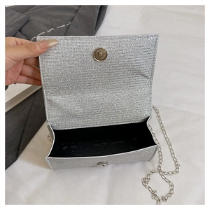Close-up of silver glitter clutch bag showing magnetic snap closure and black lining