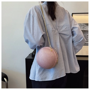Dettaglio della borsa da sera rotonda rosa con trama intrecciata e catena dorata