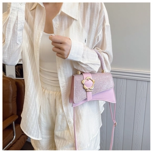 Dettaglio della borsa in pelle rosa con patta glitterata e fibbia a fiore dorato
