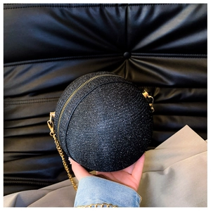 Close-up of glitter sphere evening bag featuring gold metal zipper and chain strap