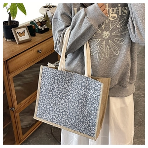 Detail of floral linen tote bag with natural fiber handles and chic blue print pattern