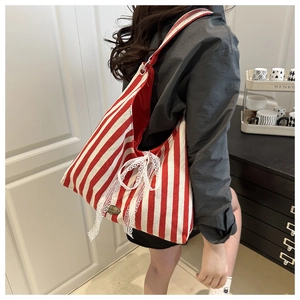 Close-up of red and white striped canvas tote with lace bow and handmade tag detail