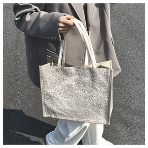 Detail of minimalist beige tote bag with 3D embossed texture and woven handles