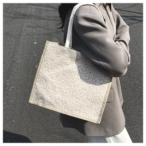 Detail of floral print linen tote bag featuring white wide straps and durable beige edging