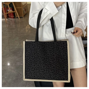 Detail of the black floral jacquard pattern and beige woven trim on this stylish tote bag