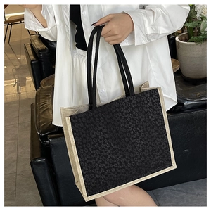 Close-up of black floral jacquard tote bag with contrasting beige canvas piping and handles