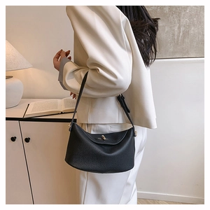 Detail of black lychee grain leather shoulder bag with gold hardware and wide strap