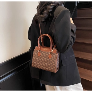Détail d'un sac bandoulière marron avec imprimé lettre M et bandoulière réglable