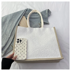 Detail of floral embroidery on linen tote bag with burlap texture and woven handles