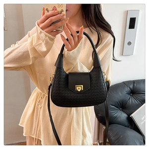 Close-up of woven leather texture on black shoulder bag with gold square clasp