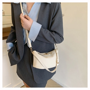Litchi texture off-white bucket bag with golden twist lock shown with gray blazer