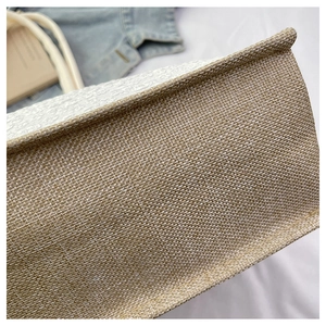 Detailed close-up of woven jute tote bag texture with reinforced beige rope handles