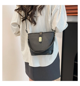 Close-up of black bucket bag featuring textured woven pattern and gold metal hardware