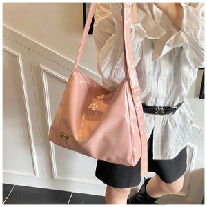 Detailed close-up of pink patent leather shoulder bag with metallic logo plaque