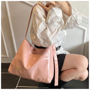 Close-up of pink glossy tote bag showing smooth texture and metallic logo detail