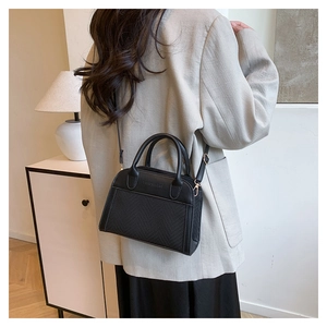 Detail of a black woven shell bag showing the Fashion & Bags embossing and leather trim