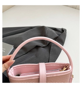 Détail de la texture tressée rose clair du sac à main avec poignée en cuir et zip doré