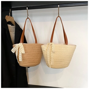 Detail of woven straw tote bags with delicate lace bows and brown leather handles