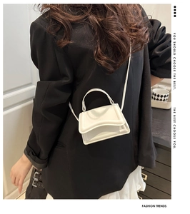 Dettaglio di una mini borsa bianca in pelle con manico tondo e tracolla sottile