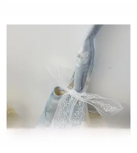 Detail of light blue satin bag featuring white lace bow and 3D floral embroidery