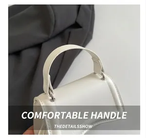Detail of white leather handbag showing smooth handle and silver D-ring metal attachment