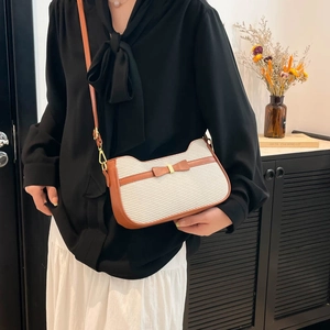 Sac bandoulière minimaliste crème à nœud et garniture en cuir marron porté par un modèle