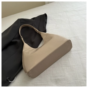 Detailed macro view of the glossy patent leather texture and metallic buckle on beige bag