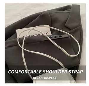 Detail eines schmalen Lederriemens und der Narbenleder-Struktur einer weißen Mini-Tasche