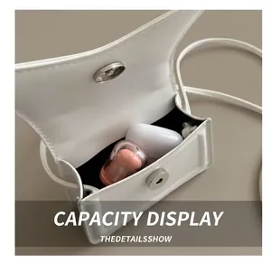 Macro view of white leather mini bag interior showing capacity for cosmetics and earbuds