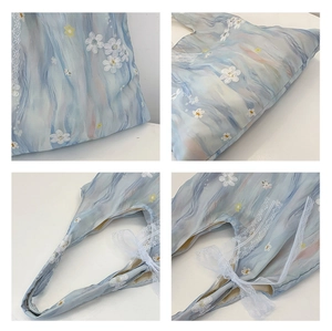 Detail of floral tote bag showing watercolor print and lace ribbon handle decorations