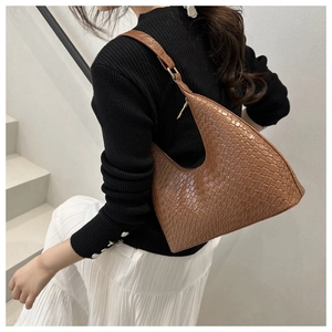 Detailed view of brown hobo bag with woven texture on a model in a minimalist setting