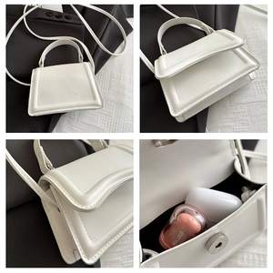 Detail view of mini white PU leather handbag showing stitching and internal capacity