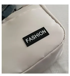 Detail des Fashion-Etiketts auf der hellen Messenger-Bag aus strukturiertem Canvas