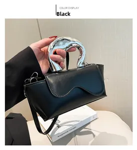 Detail of black PU leather mini bag with wavy flap and artistic silver metallic handle