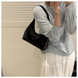 Zwarte lakleren hobo tas gestyled met een witte rok en een minimalistische gebreide trui