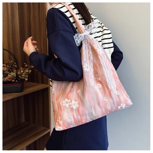 Dettaglio borsa tote in organza rosa con ricamo di margherite e fiocco in pizzo